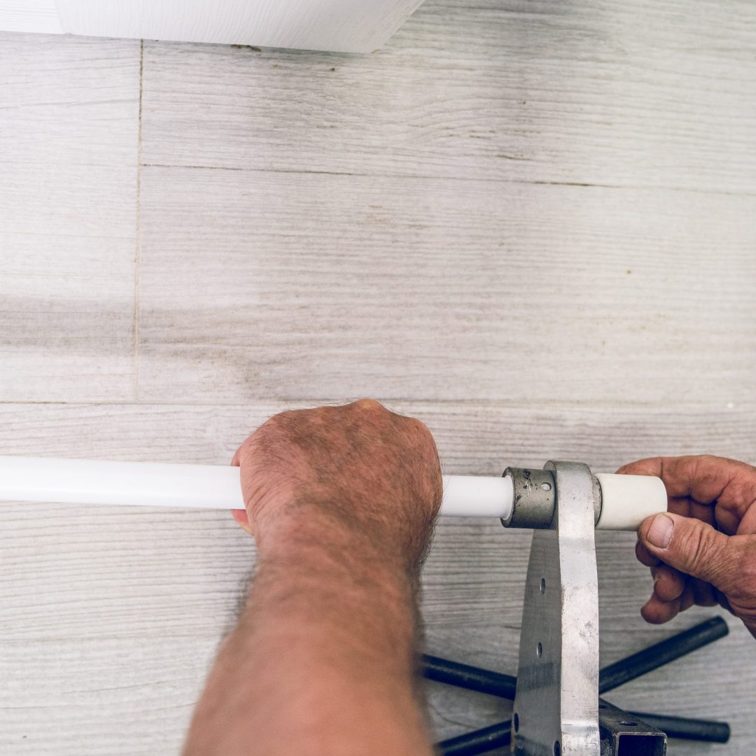 High angle on hands of plumber welding plastic pipes plumbing installation
