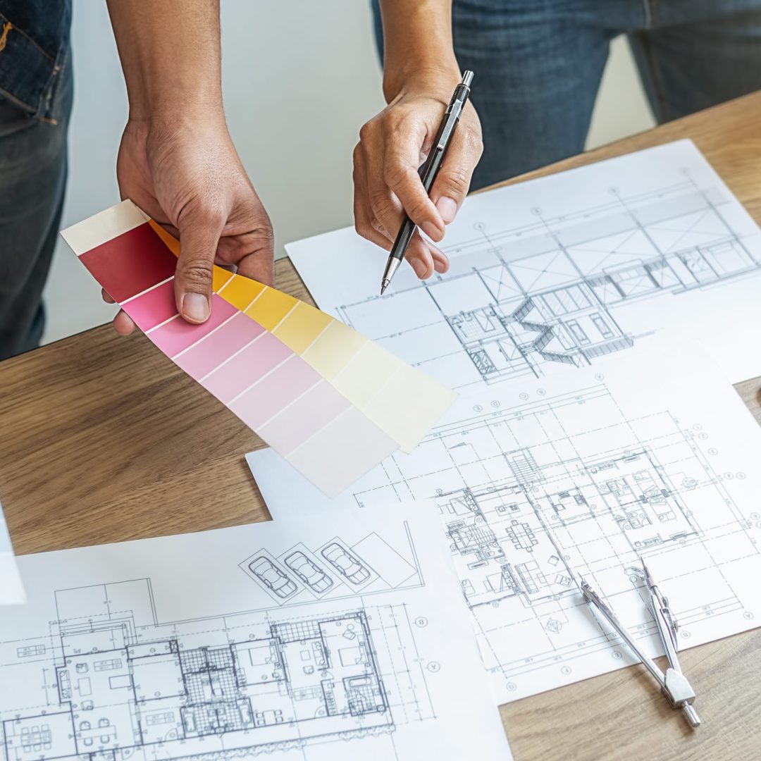 Interior designer and Architect choosing color in color swatch samples chart for house coloring selection in office with blueprint. Construction concept.