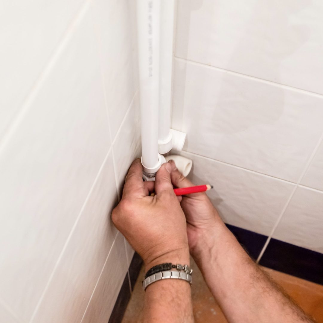 plumber tries elbow on polypropylene pipe in corner of bathroom during installation of new plumbing